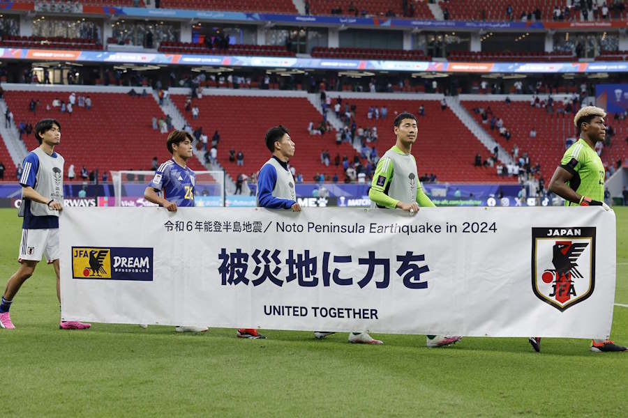日本代表の選手たちが試合後の横断幕を掲げた【写真：ロイター】